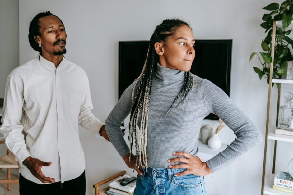 Two individuals stand side by side in a room with neutral-toned decor, displaying confident body language that suggests they are emotionally intelligent.