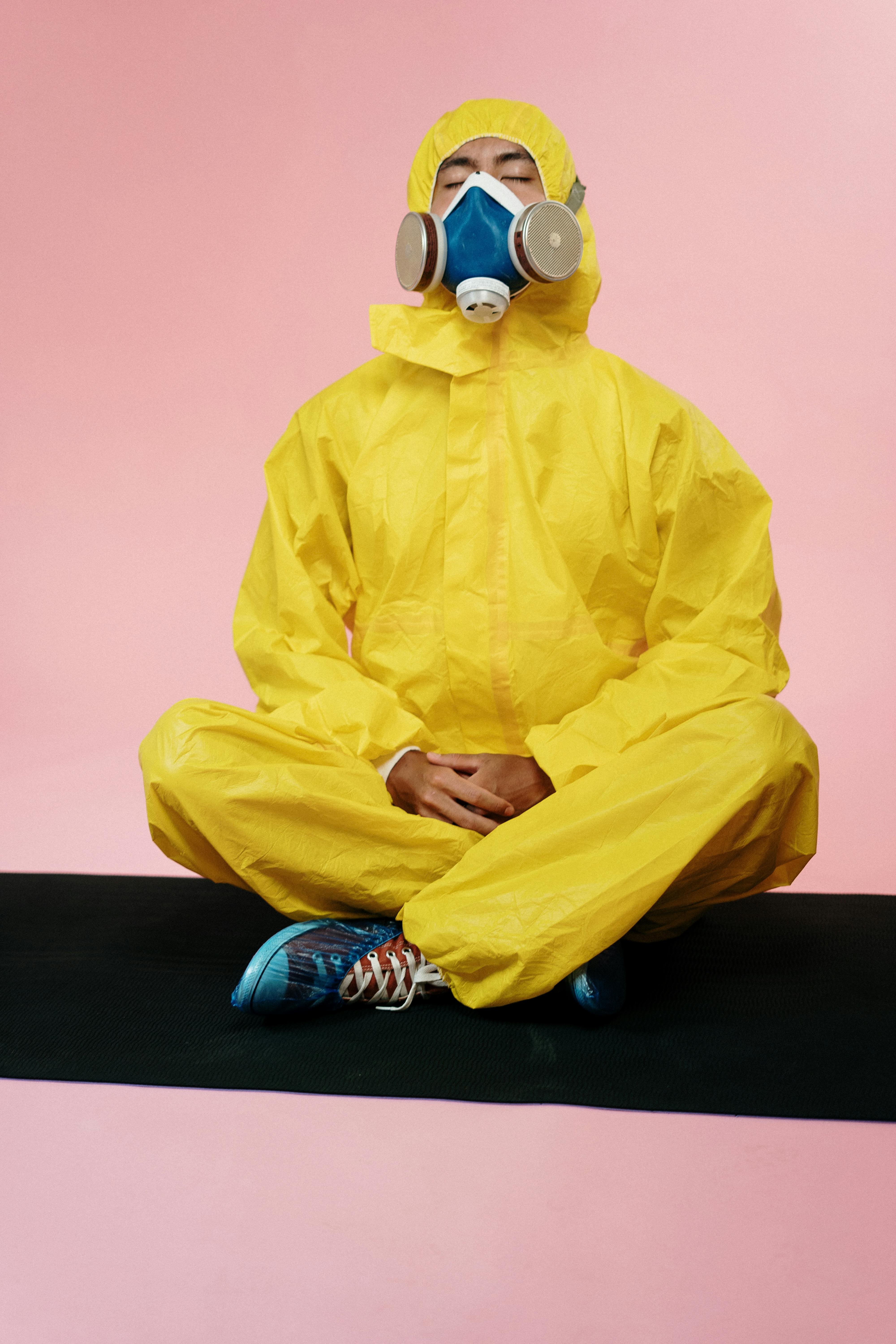 A man wearing a yellow suit and a gazmask , doing meditation,