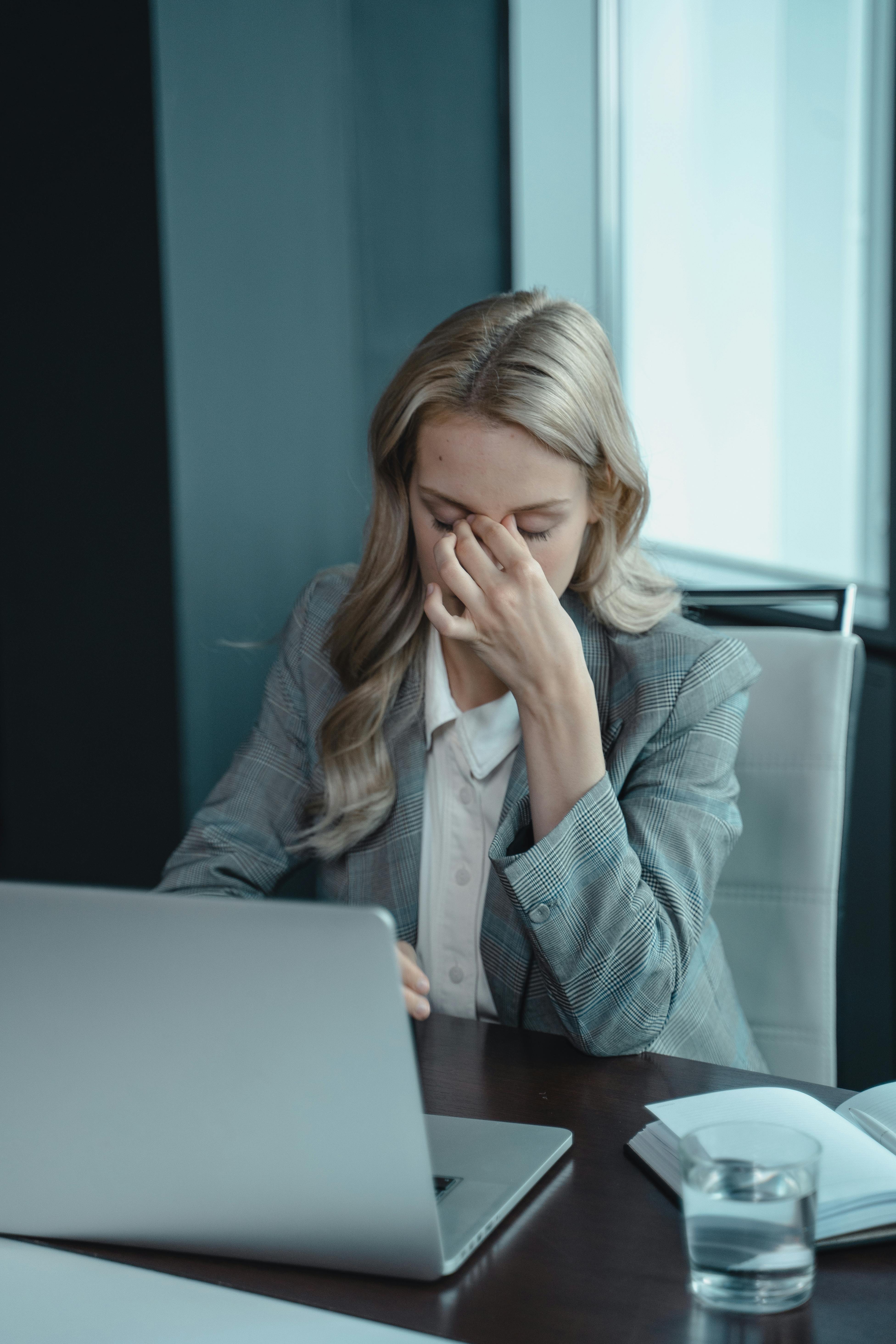 a women in an office working on a lapop , looking in a need of stress mastery