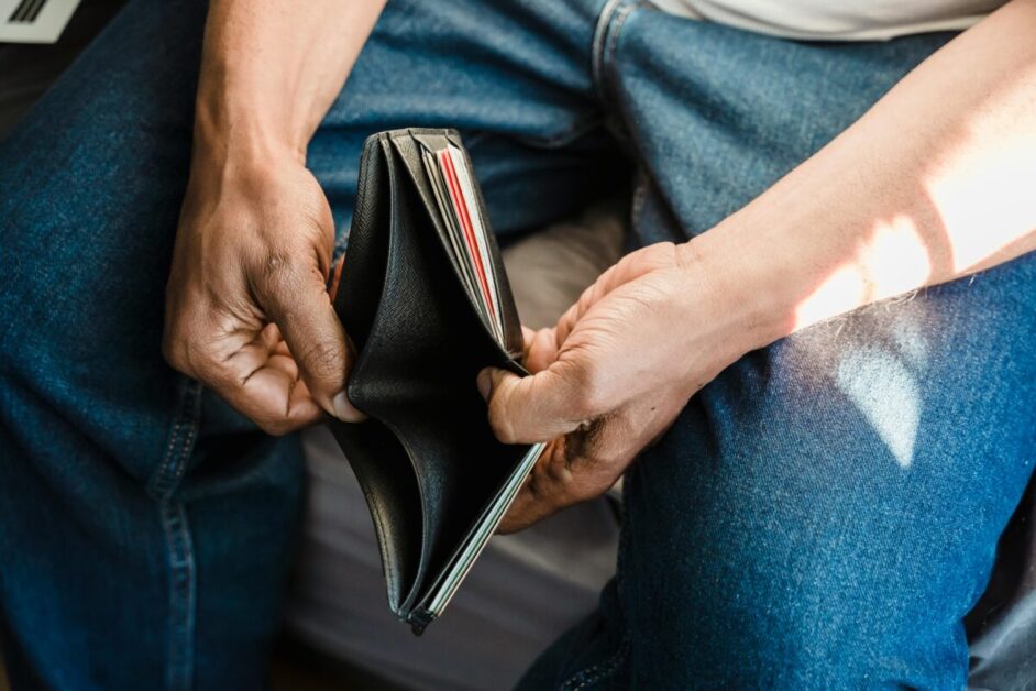 Man Looking at an Empty Wallet, Representing Financial Struggles Due to Inflation