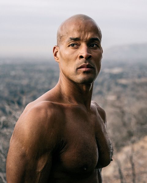 David Goggins, shirtless and with a muscular build, standing outdoors against a natural landscape, showcasing his incredible physical fitness and resilience, illustrating a motivational short story.