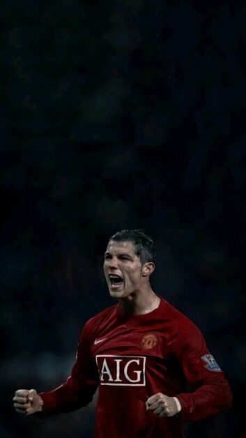 Cristiano Ronaldo, wearing a red Manchester United jersey with the logo 'AIG,' celebrates with clenched fists in a dark stadium setting, capturing a triumphant moment that could inspire a motivational short story.