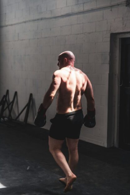 Back view of a determined boxer in a gym, symbolizing resilience, self-discipline, and the power of positive thinking in overcoming challenges.