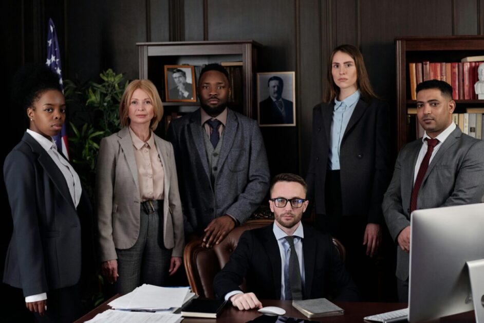 A diverse group of professionals standing together in a formal office setting, representing adaptive leadership and teamwork in a modern workplace.