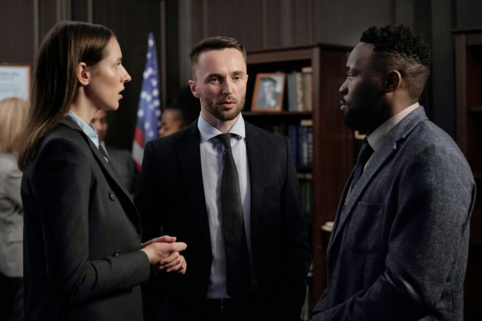 Three business professionals engaged in a focused conversation, showcasing adaptive leadership through effective communication and problem-solving.