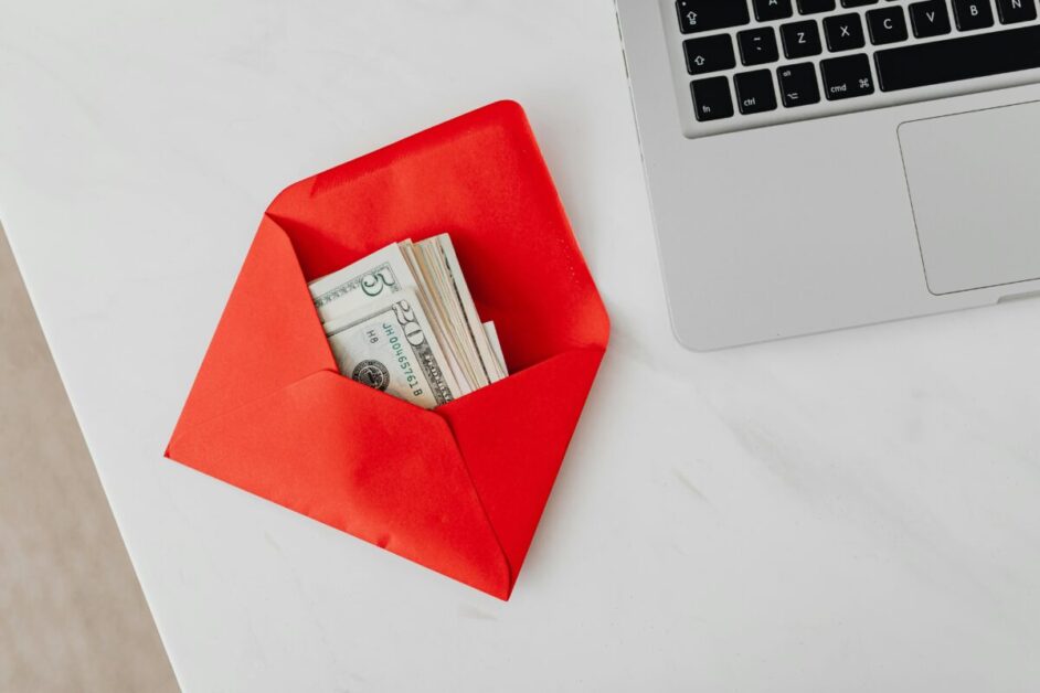 A red envelope or card containing a stack of US dollar bills, representing the concept of money-saving challenges and finding financial solutions.