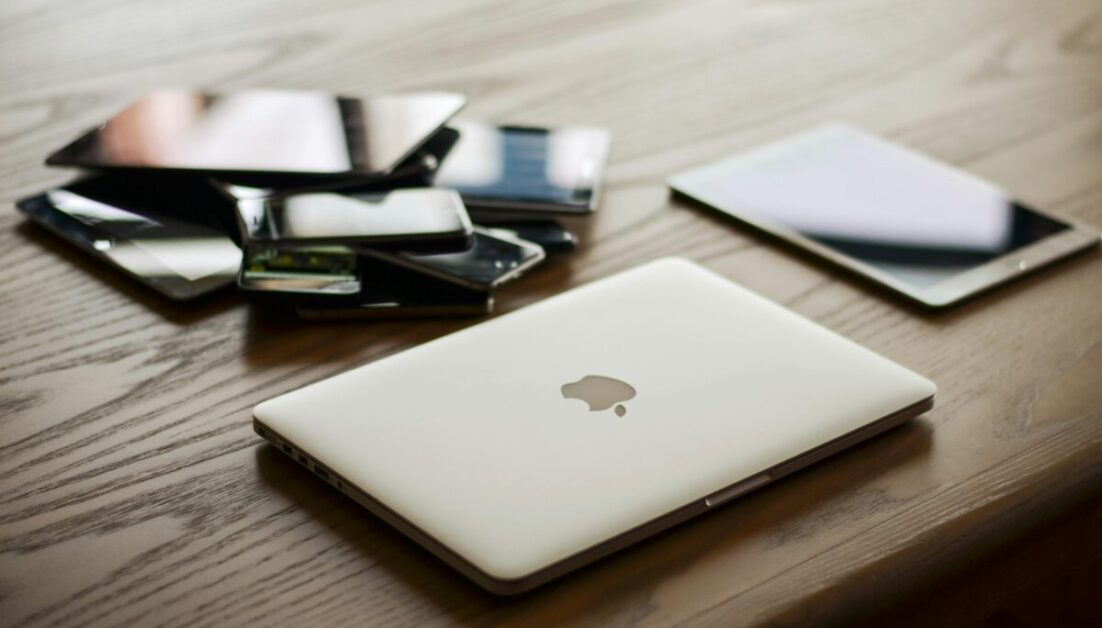 Productivity hacks: A laptop and various devices on a wooden desk.  