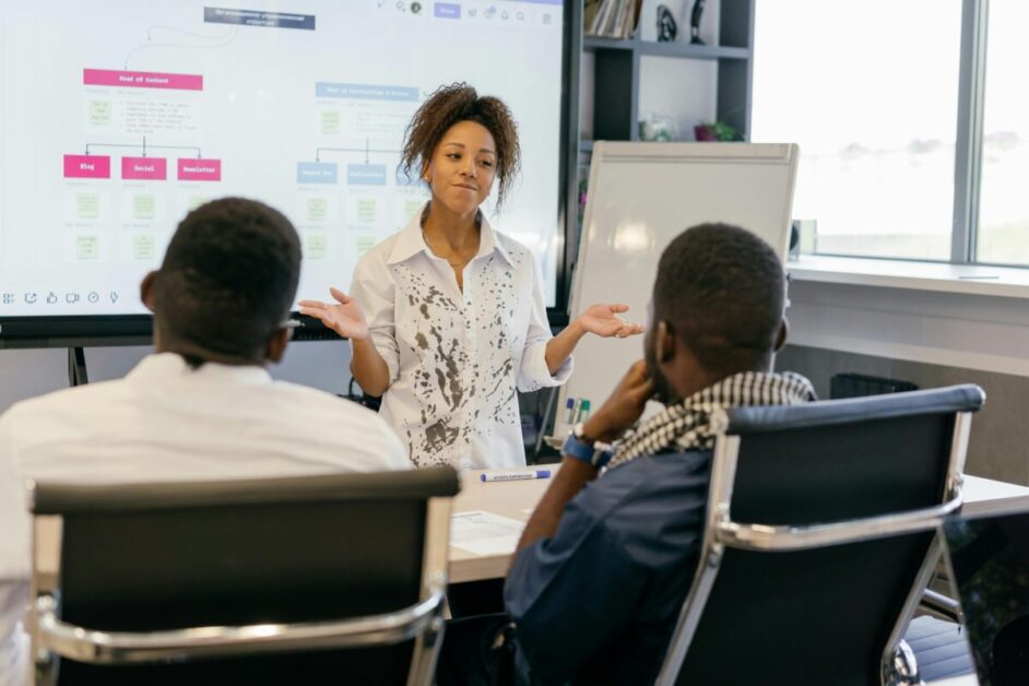 A woman presenting to a team in a professional setting, highlighting skill development through effective communication and leadership training.